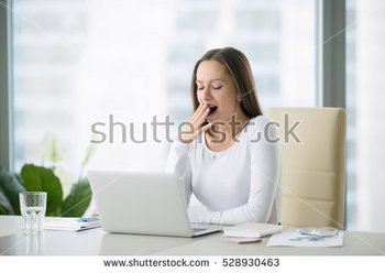 stock-photo-young-business-woman-yawning-at-a-modern-office-desk-in-front-of-laptop-covering-her-mouth-out-of-528930463.jpg